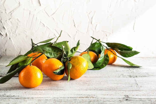 Mandarines orange avec des feuilles vertes sur un fond en bois blanc