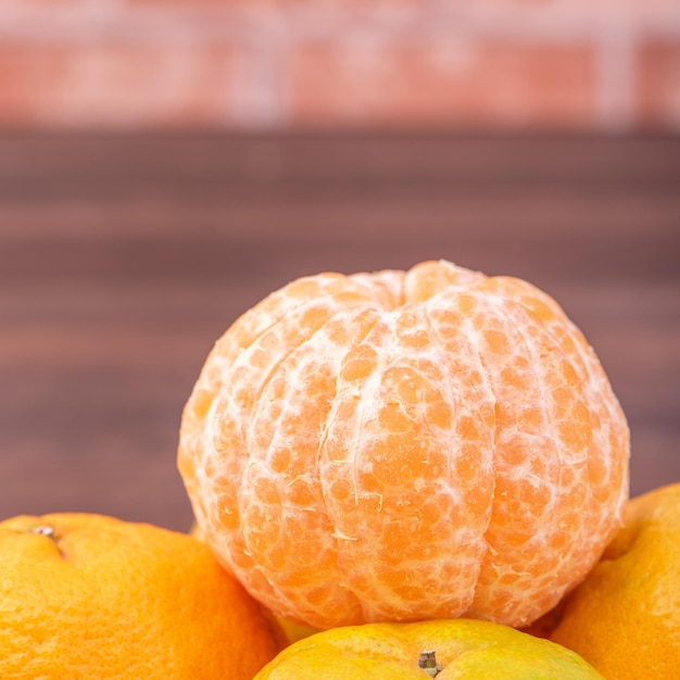 Mandarines pelées dans un panier de tamis en bambou sur une table en bois sombre avec fond de mur de briques rouges Concept de design de fruits du nouvel an lunaire chinois gros plan