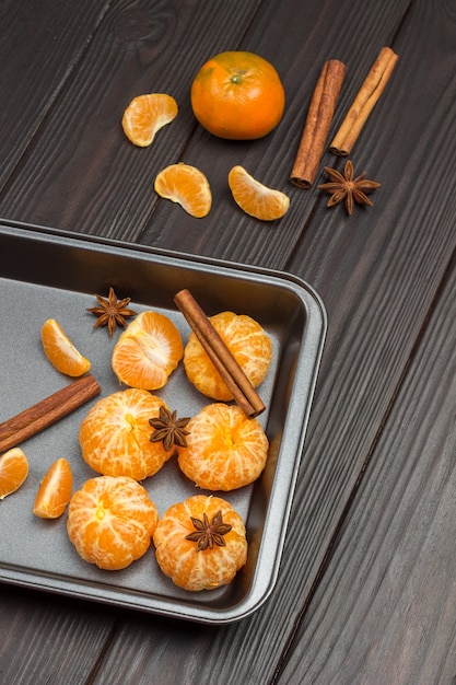 Photo mandarines pelées dans un plateau en métal. anis étoilé, bâtons de cannelle.