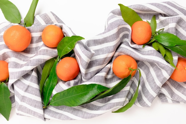 Mandarines sur une serviette en lin à rayures sur fond blanc