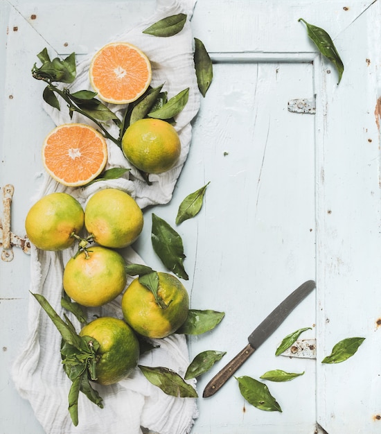 Photo mandarines turques fraîches avec des feuilles sur fond bleu en bois rustique, vue de dessus