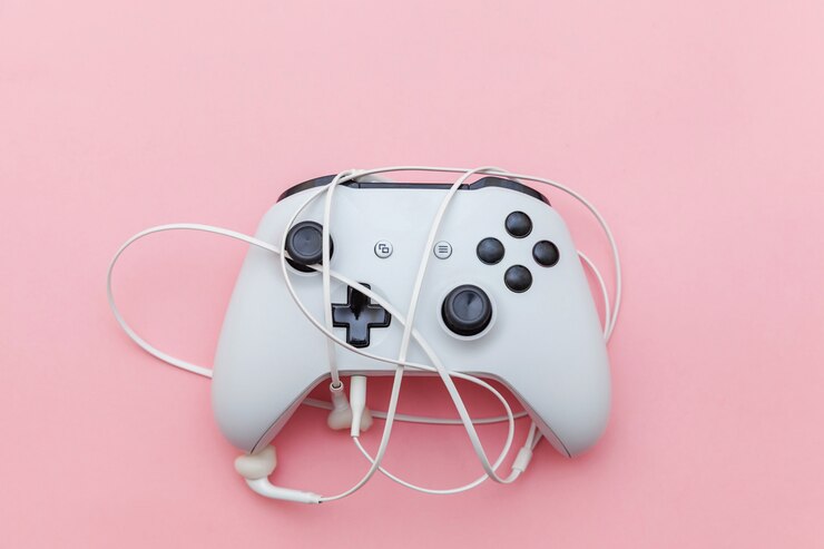 Photo manette blanche et écouteurs sur fond rose.