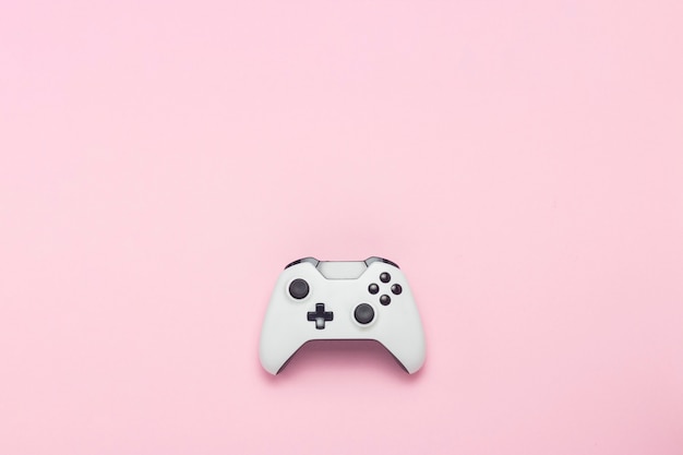 Manette de jeu blanche sur fond rose. Jeu conceptuel sur console, jeux informatiques. Mise à plat, vue de dessus.