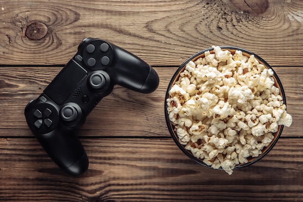 Manette de jeu et bol de pop-corn sur bois.