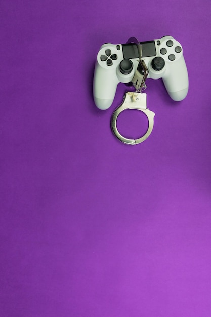 Manette de jeu vidéo et menottes isolées. Dépendance à l'image de concept de jeux