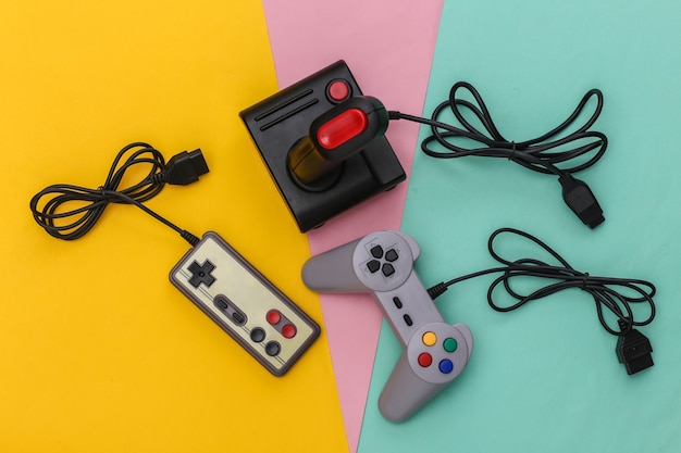 Photo manettes de jeu rétro filaires et joystick avec câble enroulé sur fond coloré. jeu vidéo, jeux. vue de dessus