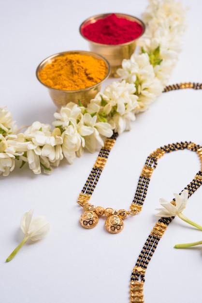 Photo mangalsutra ou collier doré à porter par une femme hindoue mariée, arrangé avec un sari traditionnel avec des fleurs de huldi kumkum et de mogra gajra, mise au point sélective