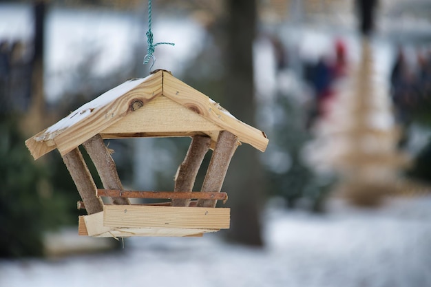 Photo un mangeoir d'oiseaux en bois en forme de petite maison suspendue à une corde dans un environnement enneigé