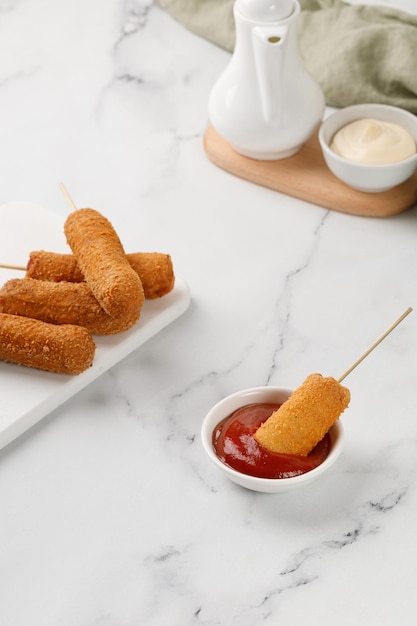 Manger du chien de maïs avec du ketchup sur fond de marbre blanc Corndog de l'alimentation de rue traditionnelle américaine