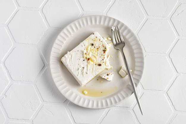 Manger du fromage Feta sur une assiette avec de l'huile d'olive au poivre vue de dessus de fond de carreaux
