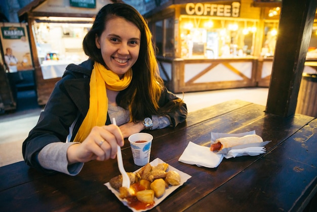 Manger de la nourriture de rue à l'extérieur sur une table en bois le soir