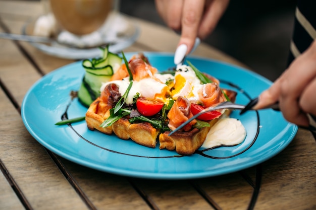 Manger des toasts gaufres avec œuf poché et saumon sur la table en bois