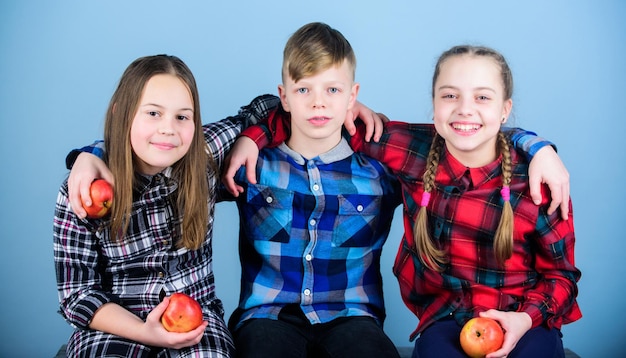 Mangez des fruits et soyez en bonne santé Amis enfants s'embrassent Mode de vie sain Amis garçons et filles dans des vêtements à carreaux similaires mangent des pommes Adolescents avec une collation saine Régime alimentaire sain et nutrition vitaminique