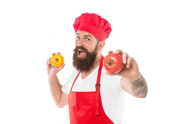 Mangez des tomates fraîches. Choisissez-en un. Concept de cuisine saine. Homme avec barbe sur fond blanc. Le chef détient des tomates. Cuire en uniforme contient des légumes. Recette de sauce tomate. Tomate mûre pour un délicieux repas.