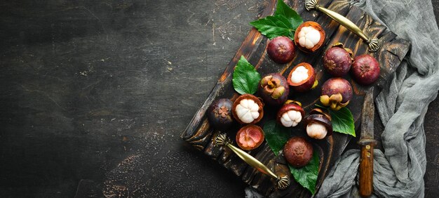 Mangoustan avec une feuille sur fond de pierre noire Fruits tropicaux Vue de dessus Espace libre pour le texte