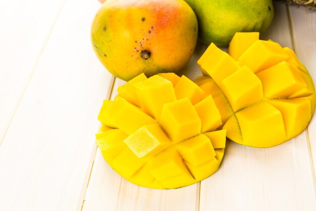 Mangue et ananas biologiques frais sur une planche de bois blanc.