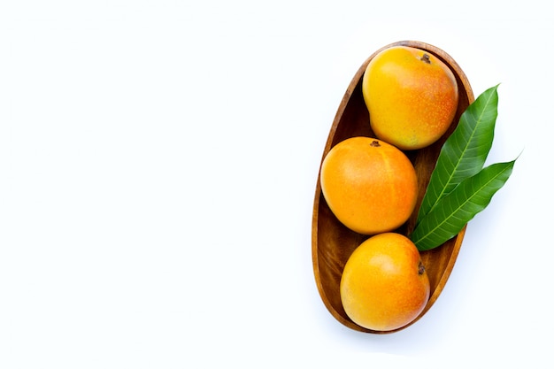 Mangue avec des feuilles dans un bol en bois