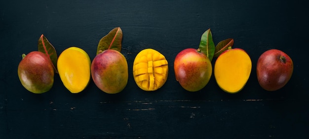 Mangue avec des feuilles sur un fond en bois noir Fruits tropicaux vue de dessus espace libre pour votre texte