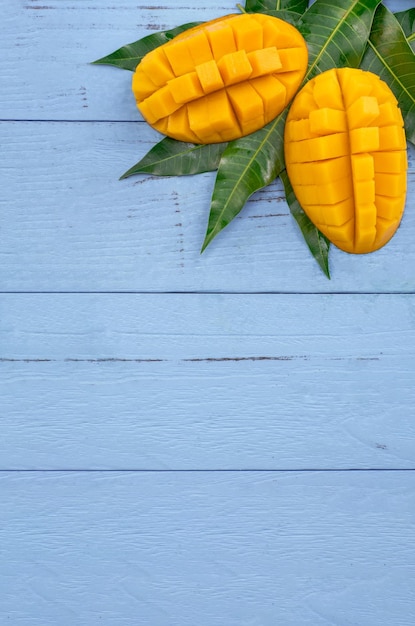 Mangue fraîche beau fruit haché avec des feuilles vertes sur fond de bois bleu vif Concept de design de fruits tropicaux Mise à plat Vue de dessus Copier l'espace