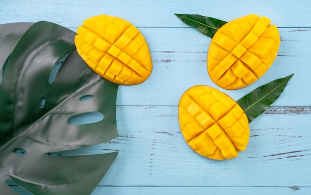 Mangue fraîche beau fruit haché avec des feuilles vertes sur fond de bois bleu vif Concept de design de fruits tropicaux Mise à plat Vue de dessus Copier l'espace