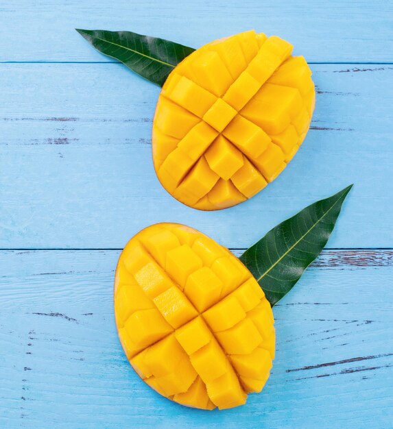 Mangue fraîche beau fruit haché avec des feuilles vertes sur fond de bois bleu vif Concept de design de fruits tropicaux Mise à plat Vue de dessus Copier l'espace