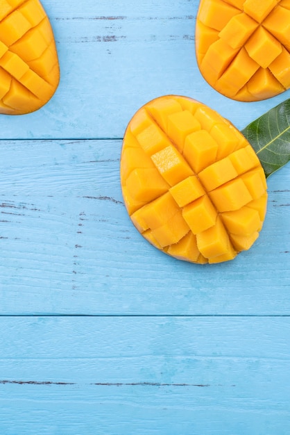 Mangue fraîche, beau fruit haché avec des feuilles vertes sur fond de table en bois foncé. Concept de design de fruits tropicaux. Mise à plat. Vue de dessus. Espace de copie