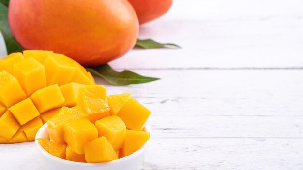 Mangue fraîche, beaux fruits hachés avec des feuilles vertes sur fond de table en bois clair