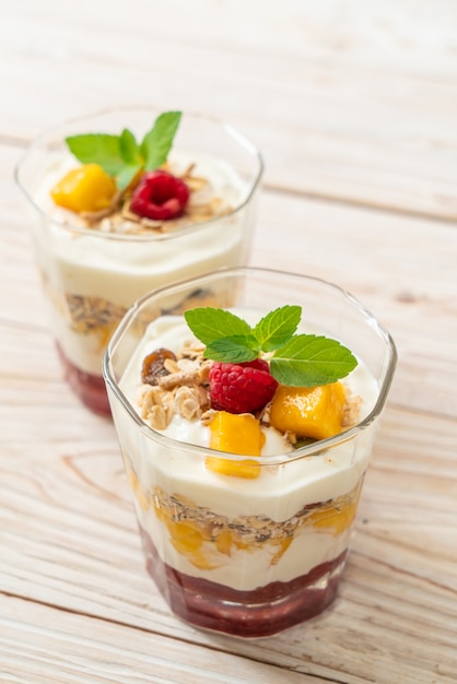 mangue fraîche faite maison et framboise fraîche avec yogourt et granola - style alimentaire sain