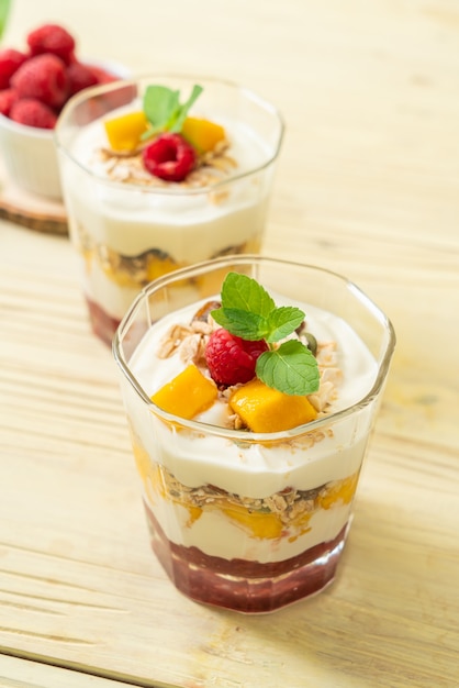 mangue fraîche faite maison et framboise fraîche avec yogourt et granola - style alimentaire sain