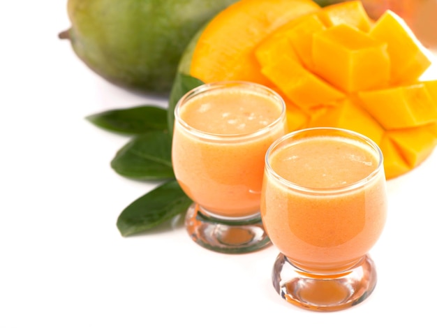 Mangue de fruits exotiques frais juteux et verres de jus sur fond blanc