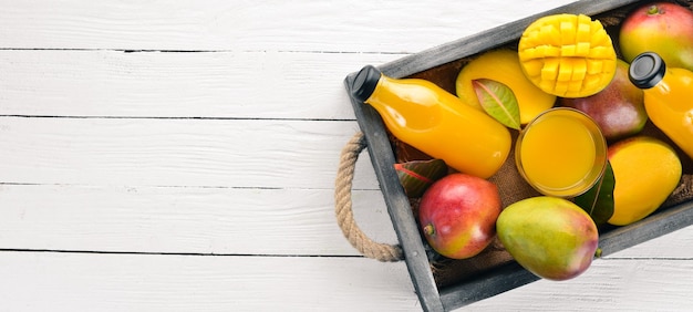 Mangue et jus dans une boîte en bois Sur un fond en bois Fruits tropicaux Vue de dessus Espace de copie gratuit