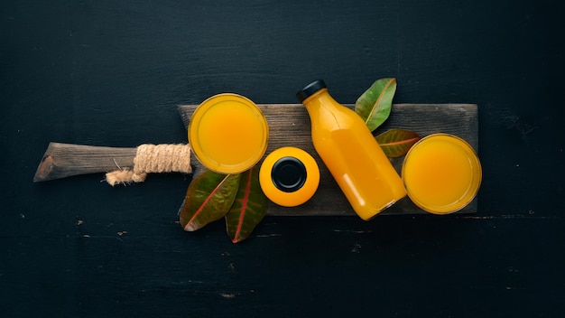 Mangue et jus de fruits frais sur fond de bois noir Fruits tropicaux vue de dessus espace libre pour votre texte