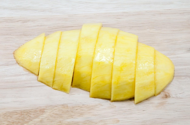 Mangue mûre coupée en morceaux sur un plancher en bois