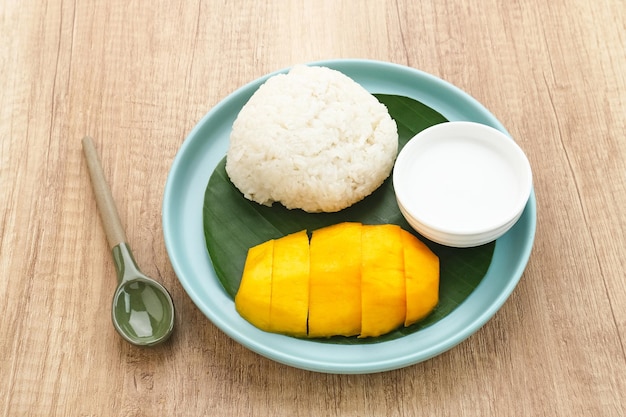 Mangue avec riz gluant, dessert thaïlandais. Servi dans une assiette blanche sur fond de bois