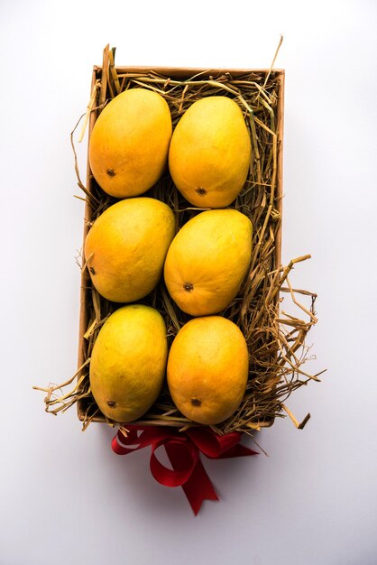 Mangues Alphonso dans une boîte-cadeau sur herbe et attachées avec un ruban rouge, mise au point sélective