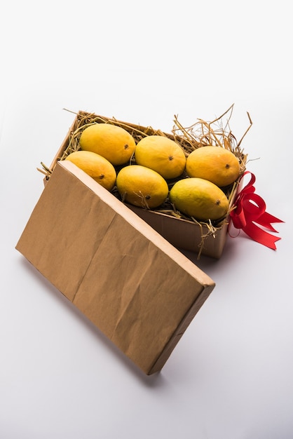 Mangues Alphonso dans une boîte-cadeau sur herbe et attachées avec un ruban rouge, mise au point sélective