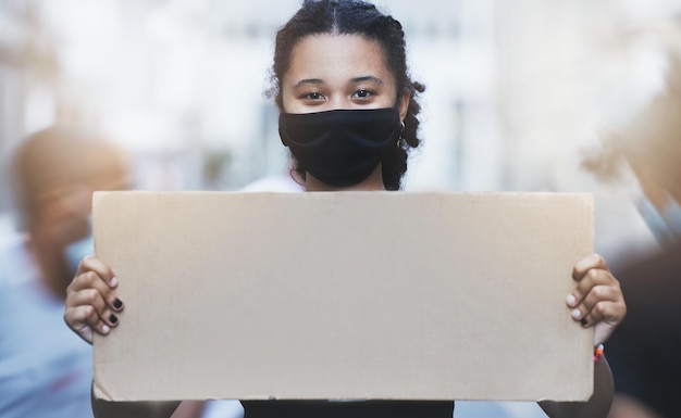 Manifestation d'activisme et fille avec une affiche avec espace de copie dans une rue avec masque facial pendant la pandémie Portrait d'un militant des droits de l'homme protestant avec un panneau vide pour l'égalité ou la justice dans la ville