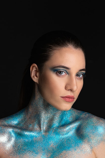 Mannequin femme fille avec des paillettes bleu vif sur la peau du visage et du corps, concept de la saison d'hiver.