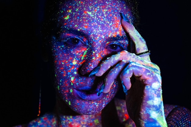 Mannequin femme en néon portrait d'un beau modèle avec un maquillage fluorescent conception artistique de danseurs disco posant dans un maquillage coloré UV isolé sur fond noir