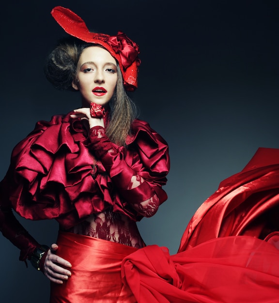 Photo mannequin glamour en costume d'élégance rouge avec chapeau rouge. prise de vue en studio.