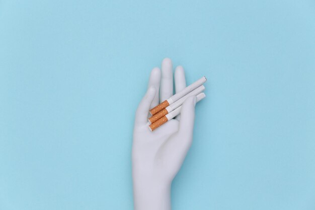 Mannequin hand holding cigarettes sur fond bleu