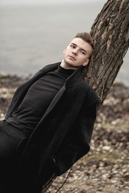 mannequin homme en manteau se trouve sur un arbre, portrait d'art de l'homme sur la plage en automne