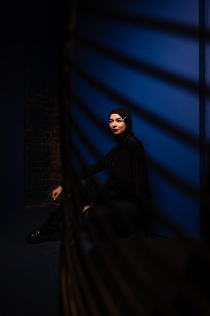 Mannequin musulman en hijab noir pose sur fond bleu en studio Islam religion photo créative