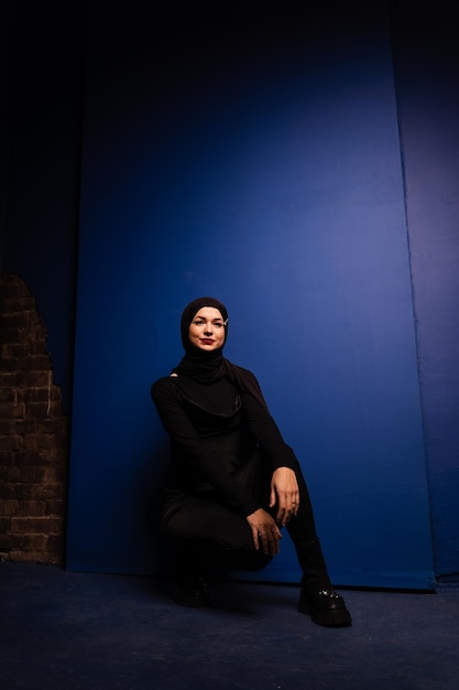 Mannequin musulman en hijab noir pose sur fond bleu en studio religion Islam