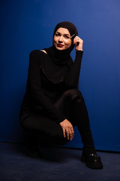 Mannequin musulman en hijab noir pose sur fond bleu en studio. religion islamique.