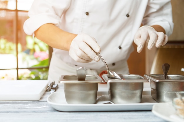 Mans hand holding cuillère cuillère à côté de contenants de sauce, le chef choisit la saveur pour la cuisine professionnelle de la viande ...