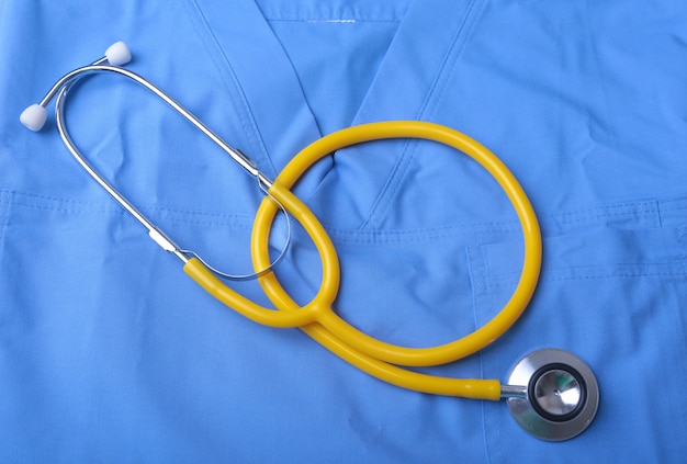 Photo manteau de docteur avec stéthoscope médical sur le bureau