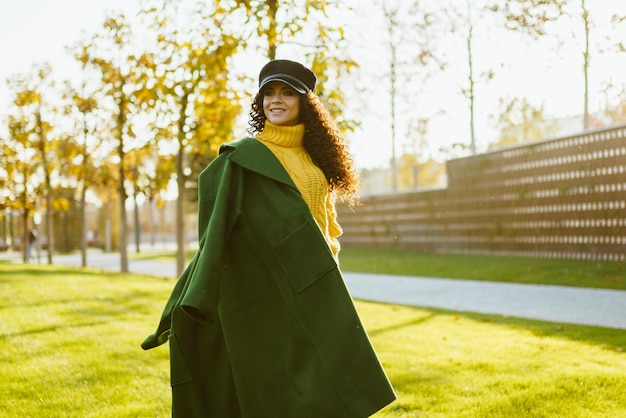 Manteau slushka sur l'épaule de la fille avec des boucles sombres sous le képi noir tombant sur le pull de couleur jaune vif