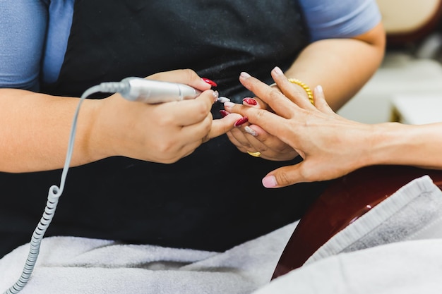 La manucure applique une perceuse à lime à ongles électrique pour la manucure sur les doigts féminins