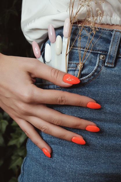 Manucure au néon lumineux sur les mains des femmes sur le fond de la conception des ongles en jeans